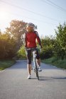 Mature cyclist with racing bicycle on rural road — Stock Photo