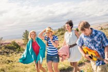 Young man and female friends playing ukulele and walking in hills, Bridger, Montana, USA — Stock Photo
