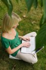 Girl on computer in garden — Stock Photo