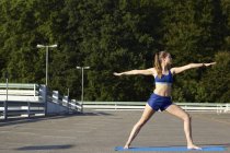 Jeune femme pratiquant le yoga dans un parking urbain — Photo de stock