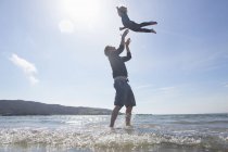 Отец бросает сына в воздух на пляже, Лох-Эйшорт, остров Скай, Гебриды, Шотландия — стоковое фото