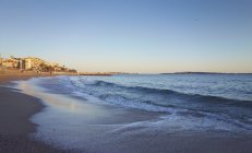 Plage de sable pittoresque avec bâtiments hôteliers et personnes en arrière-plan, Côte d'Azur, Cannes, France — Photo de stock