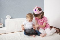 Девочка наблюдает за малышом, играющим в цифровой планшет — стоковое фото