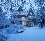 Casa e quintal iluminados cobertos de neve — Fotografia de Stock