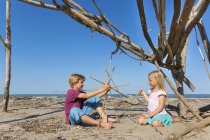 Boy and his sister constructing a circular structure from driftwood, Caleri Beach, Veneto, Italy — Stock Photo