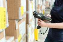 Обрезанный вид работника склада с помощью сканера штрих-кода на коробке в распределительном складе — стоковое фото
