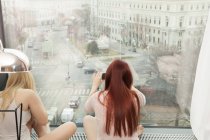 Young woman taking photograph by hotel window with view, Vienna, Austria — Stock Photo
