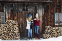 Two young female friends chatting outside wooden cabin — Stock Photo