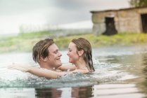 Casal jovem romântico salpicando na fonte termal Secret Lagoon (Gamla Laugin), Fludir, Islândia — Fotografia de Stock