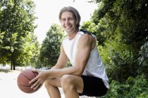 Retrato del jugador de baloncesto masculino tomando un descanso en el parque - foto de stock