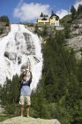 Молодой человек делает селфи на смартфоне перед водопадом Точе, Формацца, Вербания, Пьемонте, Италия — стоковое фото