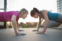 Two women training, doing push ups on stairway — Stock Photo