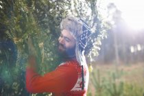 Junger Mann trägt Weihnachtsbaum auf Schultern im Wald — Stockfoto