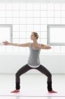 Молода жінка стоїть в позі йоги — стокове фото