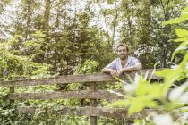 Портрет взрослого мужчины, опирающегося на садовый забор — стоковое фото