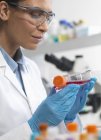 Биолог женских клеток держит фляжку, содержащую стволовые клетки, культивируемые в красной среде роста — стоковое фото