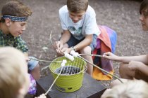 Gruppo di ragazzini che brindano ai marshmallow sul barbecue a secchio — Foto stock