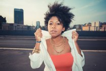 Junge Frau hält Blusenkragen auf Dach-Parkplatz hoch — Stockfoto