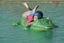 Menina nova que relaxa no inflável na piscina — Fotografia de Stock