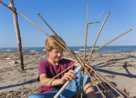 Boy constructing a circular structure from driftwood, Caleri Beach, Veneto, Italy — Stock Photo