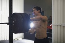 Young man training with barbells in gym — Stock Photo