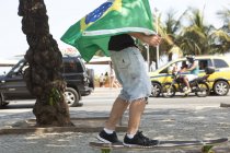 Junger mann skateboarding in brasilianischer flagge, copacabana, rio de janeiro, brasilien — Stockfoto