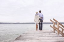 Älteres Paar steht auf Seebrücke, Blick auf Aussicht, Rückansicht — Stockfoto