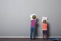 Vista trasera del hermano y la hermana pequeña empezando a pintar la pared - foto de stock