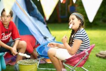 Sorella e fratello brindare marshmallow davanti alla tenda fatta in casa in giardino — Foto stock