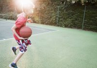 Menino jogando basquete no backlit no parque — Fotografia de Stock