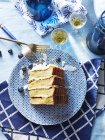 Slice of four stack cake with blueberries on blue plate — Stock Photo