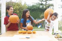 Siblings playing with pumpkins in dining room — Stock Photo