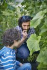 Father and son smelling plants on allotment — Stock Photo