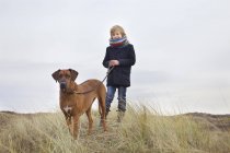 Хлопчик гуляє зі своїм собакою в піщаних дюнах на узбережжі — стокове фото