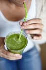Woman drinking green smoothie with straw — Stock Photo