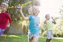 Троє дітей, що працюють з іграшкового літака в саду — стокове фото
