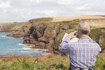 Hombre tomando fotografías, Ruta Costera cerca de Marloes, Parque Nacional de la Costa de Pembrokeshire, Gales, Reino Unido - foto de stock