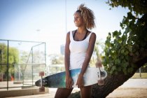 Portrait of young woman holding skateboard — Stock Photo