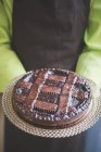 Официант несет тарелку шоколадного торта, обрезанный кадр — стоковое фото