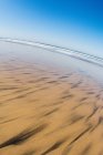 Sable avec vagues de surf océaniques au loin — Photo de stock