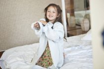 Ritratto di giovane ragazza seduta sul letto con camicia bianca oversize — Foto stock