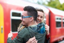 Heterosexuelles Paar umarmt sich am Bahnhof und lächelt — Stockfoto