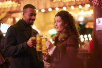 Paar in der Nacht mit Glas auf Bier anstoßen — Stockfoto