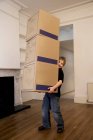 Um menino segurando uma pilha de três caixas — Fotografia de Stock
