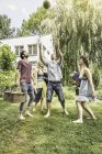 Друзья играют в мяч с арбузом в саду — стоковое фото