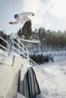 Hombre snowboarder saltando hacia atrás desde barandillas - foto de stock