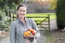 Portrait of woman holding apples and pumpkin at Thornbury Castle, South Gloucestershire, UK — Stock Photo