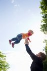Father throwing baby daughter mid air in park — Stock Photo
