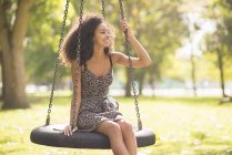 Portrait of young woman sitting on tire swing — Stock Photo