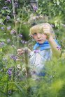 Мальчик наряжается и играет с растениями в саду — стоковое фото